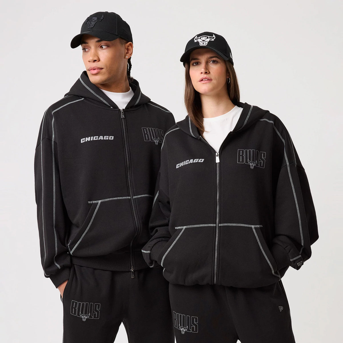 New Era Chicago Bulls NBA Graphic Black Pullover Hoodie, front view on-model displaying the word Chicago and an embroidered Bulls logo on the chest, intricate stitching details along the seams, and the hood of the black hoodie pulled up slightly.