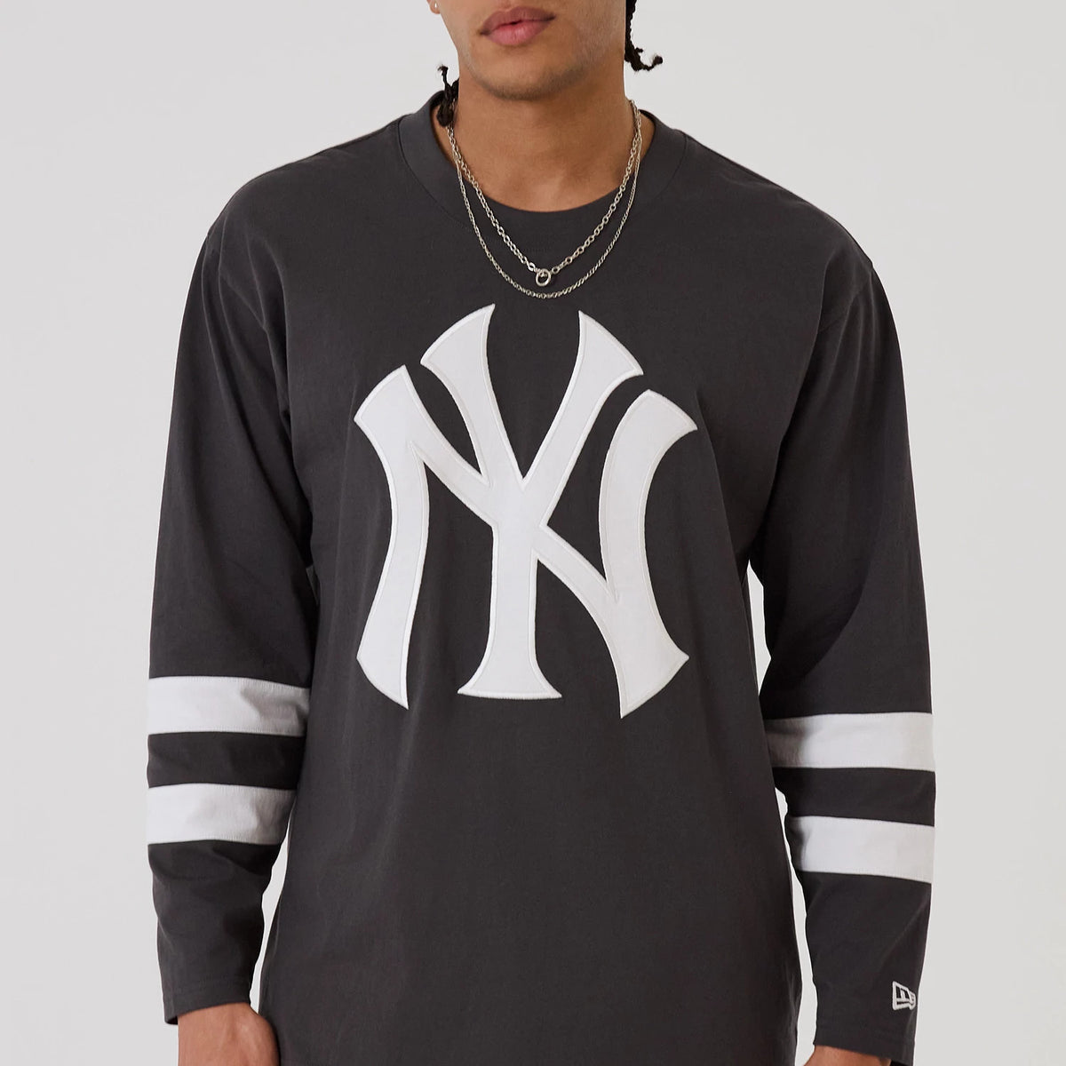The model is wearing this MLB League Essential New York Yankees Oversized Jersey in charcoal. 3