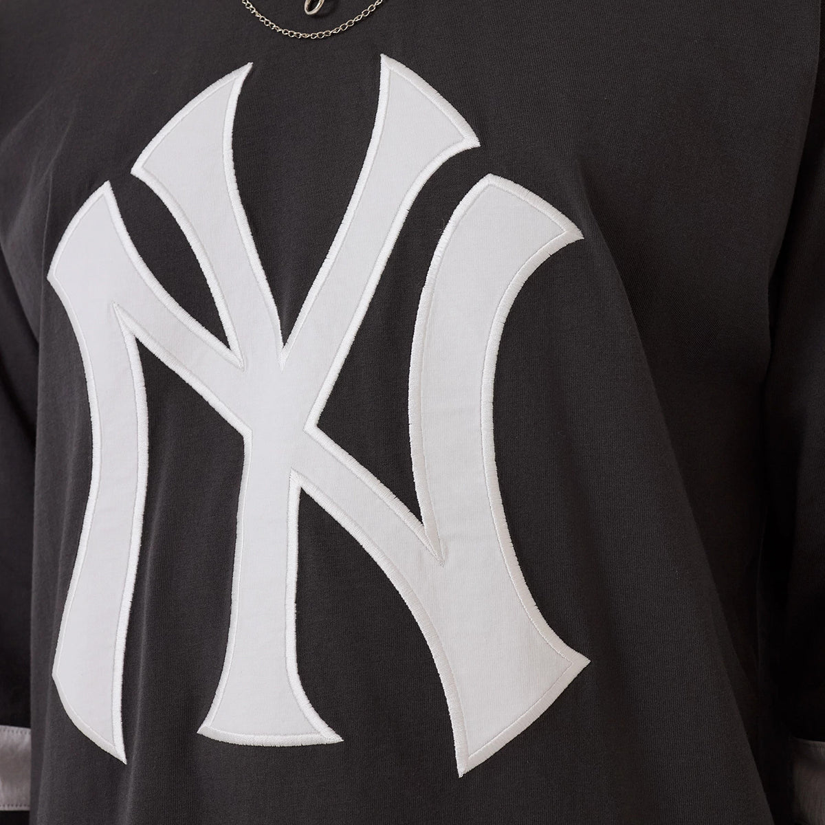 The model is wearing this MLB League Essential New York Yankees Oversized Jersey in charcoal. 4