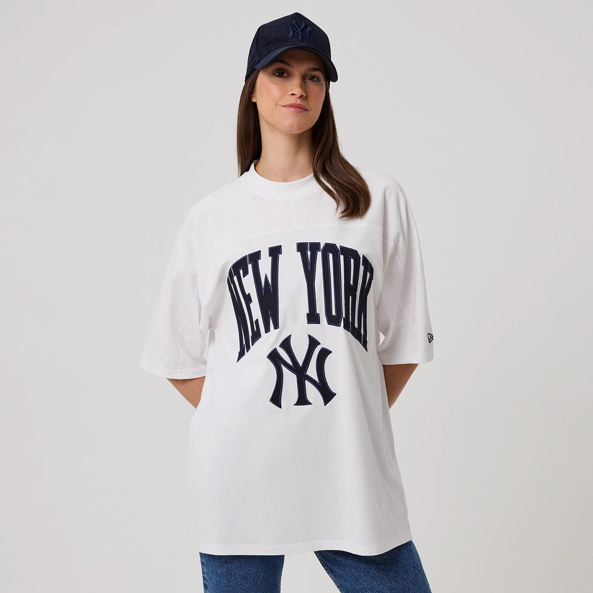 New Era New York Yankees MLB Arch Graphic White Oversized T-Shirt, front view on-model displaying the navy New York arch graphic across the chest, large NY logo below, and a small embroidered New Era logo on the sleeve.