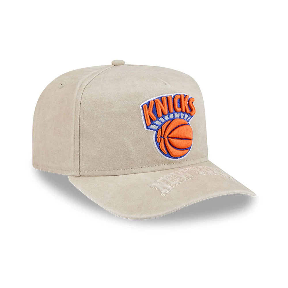 New York Knicks NBA Light Beige New Era 9FIFTY A-Frame Snapback Adjustable Cap, three-quarter view showing the raised orange and blue Knicks logo embroidered on the front panel, with a curved beige visor and New Era script on the edge.