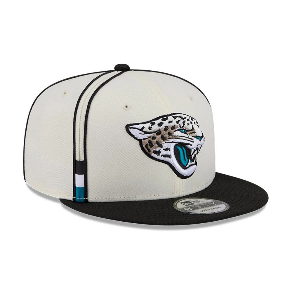 Jaguars NFL Rivalry 2026 White & Black New Era 9FIFTY Snapback Adjustable Cap, front view showing the raised embroidered jaguar logo in white, black, and teal on the cream front panel, with a contrasting black flat visor and 9FIFTY size sticker.