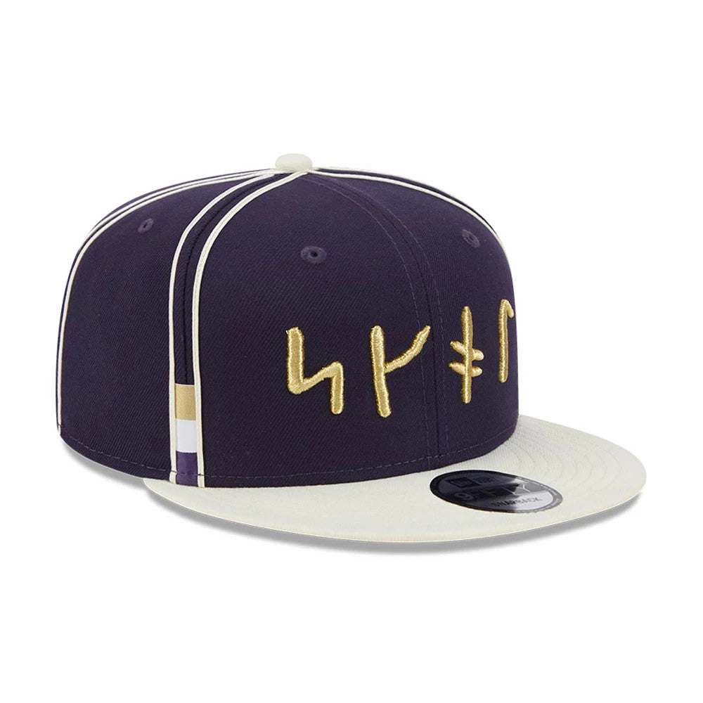 Vikings NFL Rivalry 2026 Dark Purple New Era 9FIFTY Snapback Adjustable Cap, three-quarter view showing gold embroidered runes on the dark purple front panel, white flat visor with a 9FIFTY size sticker, and white piping along the seams.