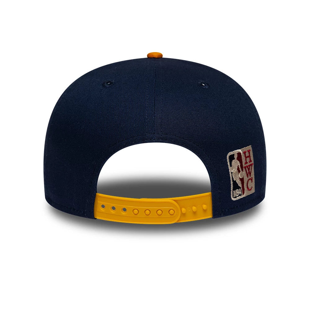 Warriors NBA Hardwood Classic Dark Blue New Era 9FIFTY Snapback Adjustable Cap, rear view showing the embroidered NBA Hardwood Classics logo on the right panel, a structured dark blue crown, and a yellow adjustable snapback closure.