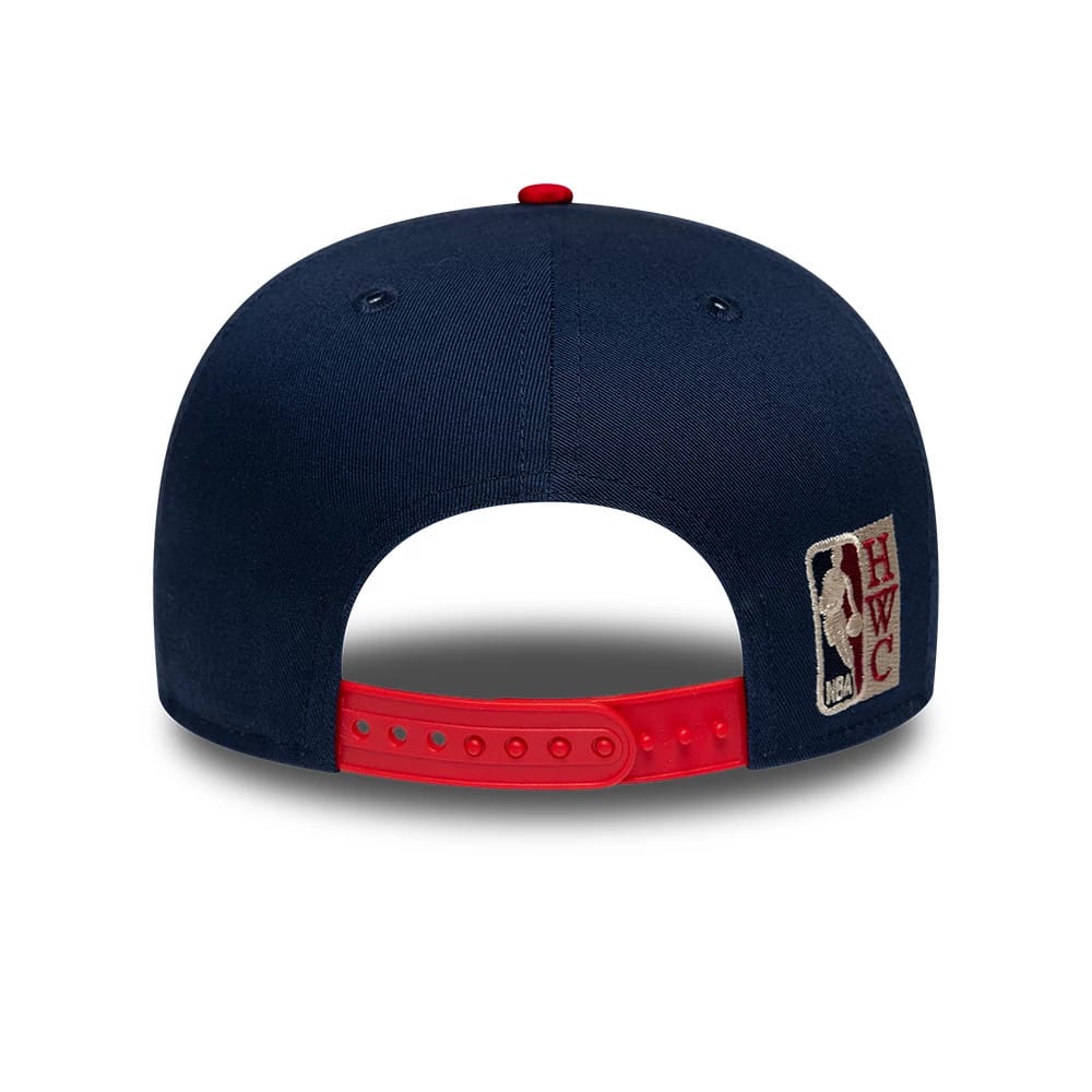 Nets NBA Hardwood Classic Dark Blue New Era 9FIFTY Snapback Adjustable Cap, rear view showing the embroidered HWC logo at the bottom right of the navy crown, with a red top button and matching red adjustable snapback closure.