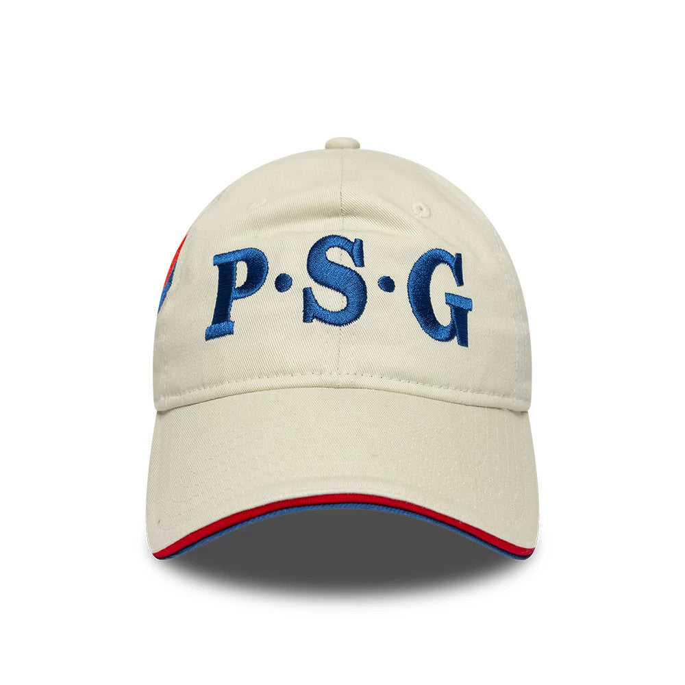 Paris Saint-Germain 86 Light Beige New Era 9TWENTY Adjustable Cap, front view featuring large blue embroidered P.S.G letters on the structured beige crown, with a curved visor accented by red and blue trim on the edge.