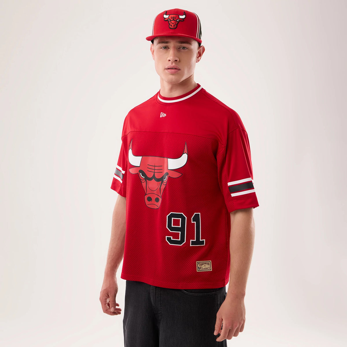 New Era Chicago Bulls NBA Hardwood Classic Mesh Oversized Red T-Shirt, front view on-model featuring a large Chicago Bulls logo on the chest, number 91 below it, striped sleeves, and an embroidered New Era logo near the collar.
