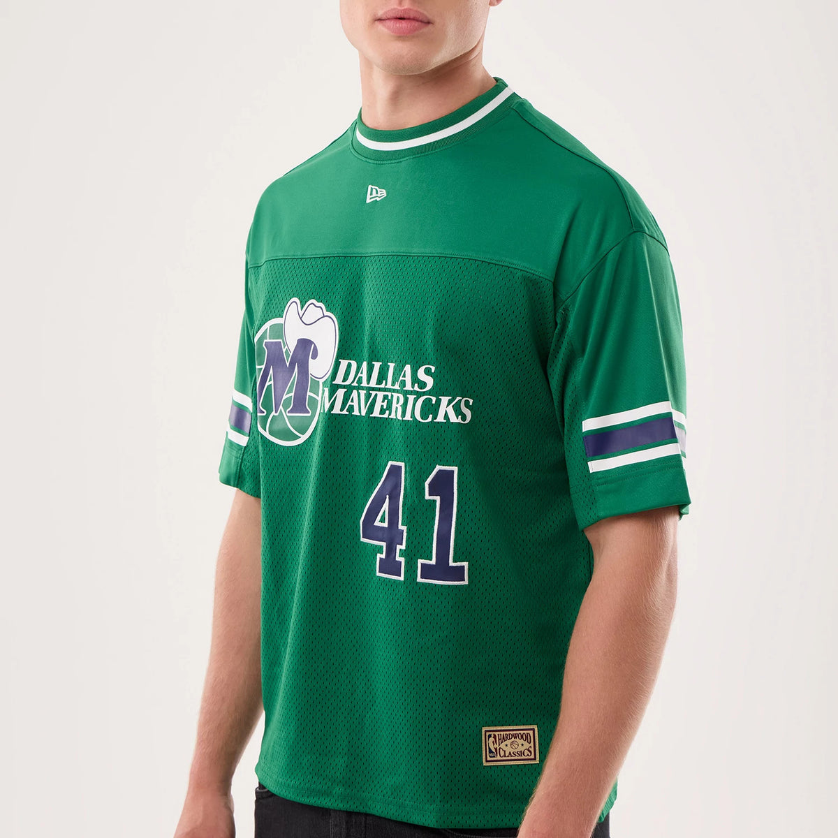 New Era Dallas Mavericks NBA Hardwood Classic Mesh Oversized Green T-Shirt, front view on a model displaying the large printed Mavericks logo and number 41 in white and purple, double striped sleeves, and an embroidered New Era logo on the chest.