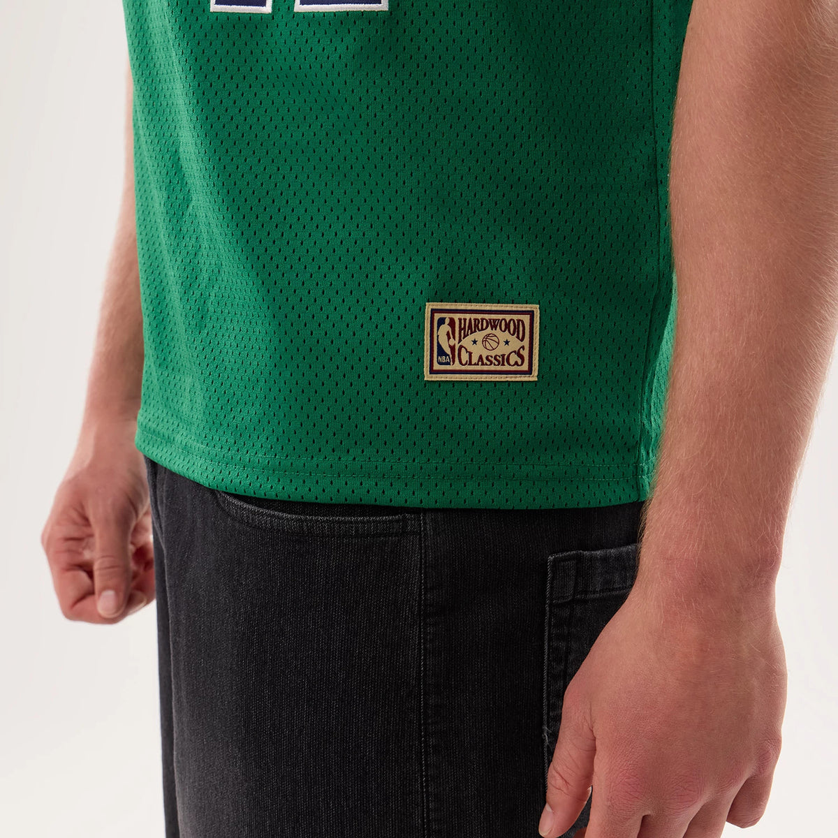New Era Dallas Mavericks NBA Hardwood Classic Mesh Oversized Green T-Shirt, three-quarter view showing the hardwood classics patch near the hem, green mesh fabric, and part of a number in white outline on the front.