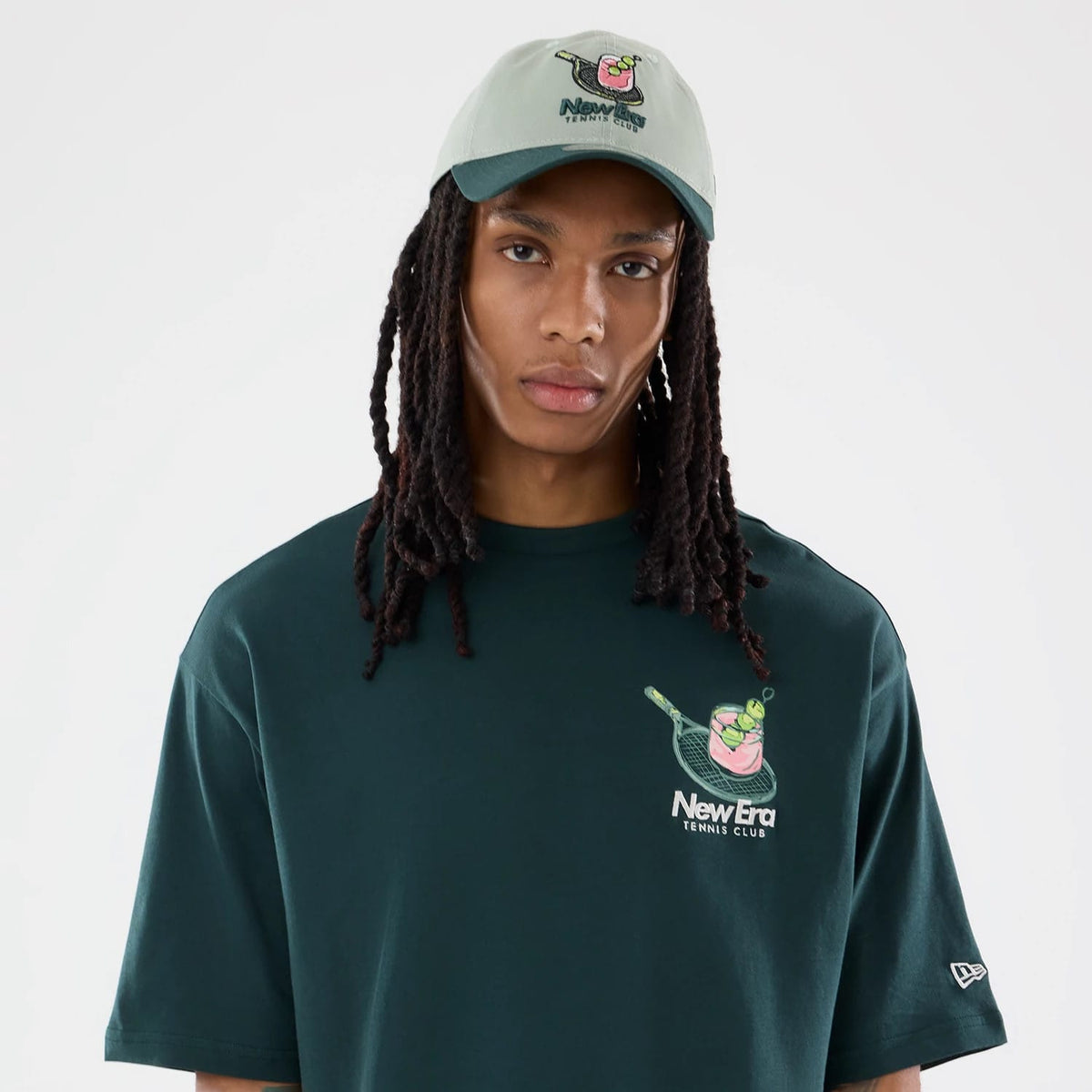 The model is wearing this New Era Tennis Graphic Oversized T-Shirt in dark green. 3