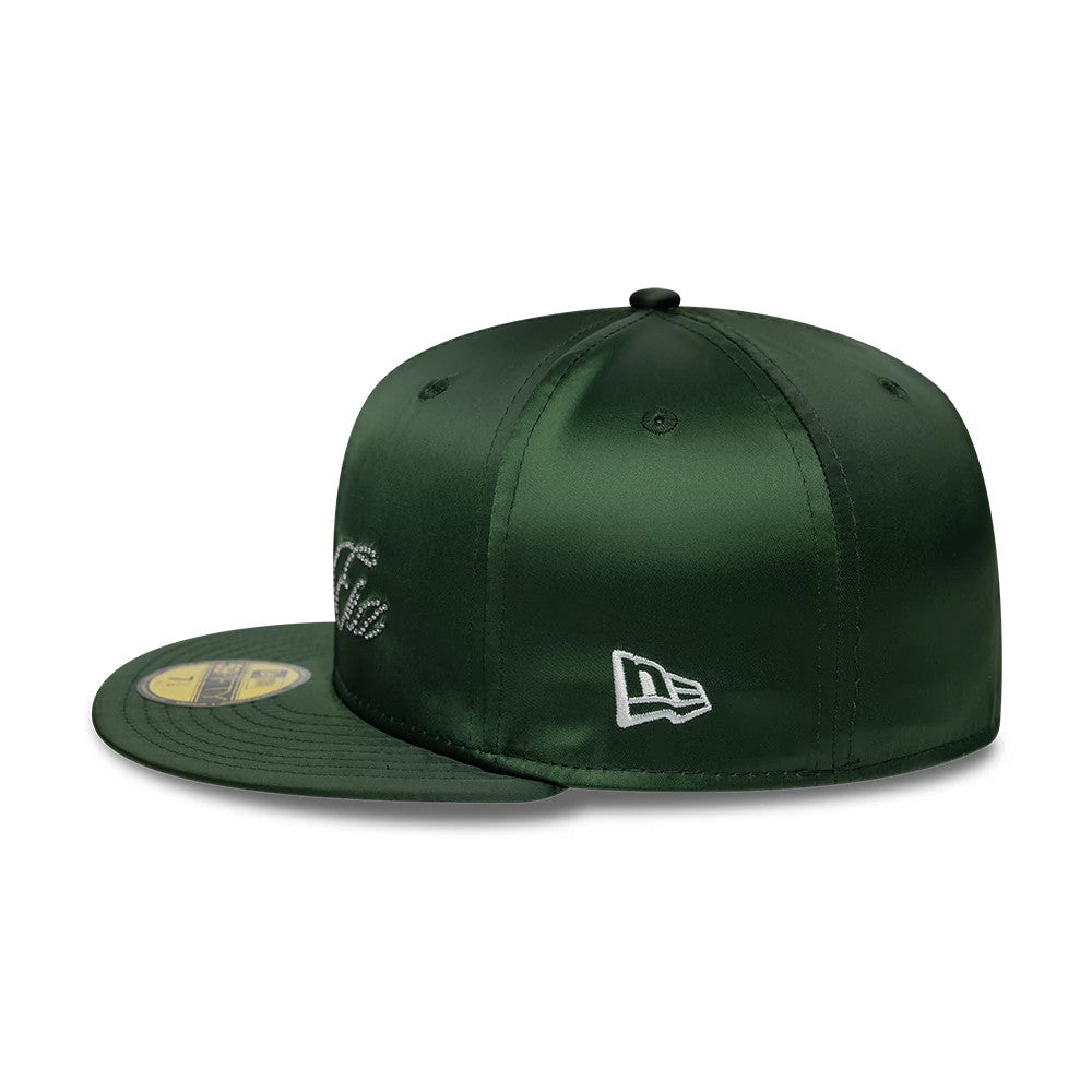New Era Satin Diamante Dark Green 59FIFTY Fitted Cap, side view showing the white embroidered New Era flag logo on the left side of the structured dark green satin crown with a flat dark green visor and 59FIFTY size sticker.