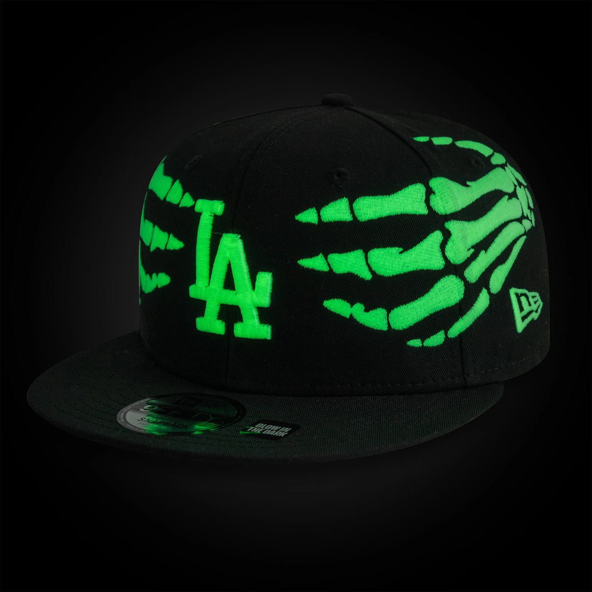 Dodgers MLB Halloween Glow In The Dark Hands Black New Era 9FIFTY Snapback Adjustable Cap, three-quarter view showing the green glow-in-the-dark skeletal hand graphics on the side panels, with the raised LA logo on the front.