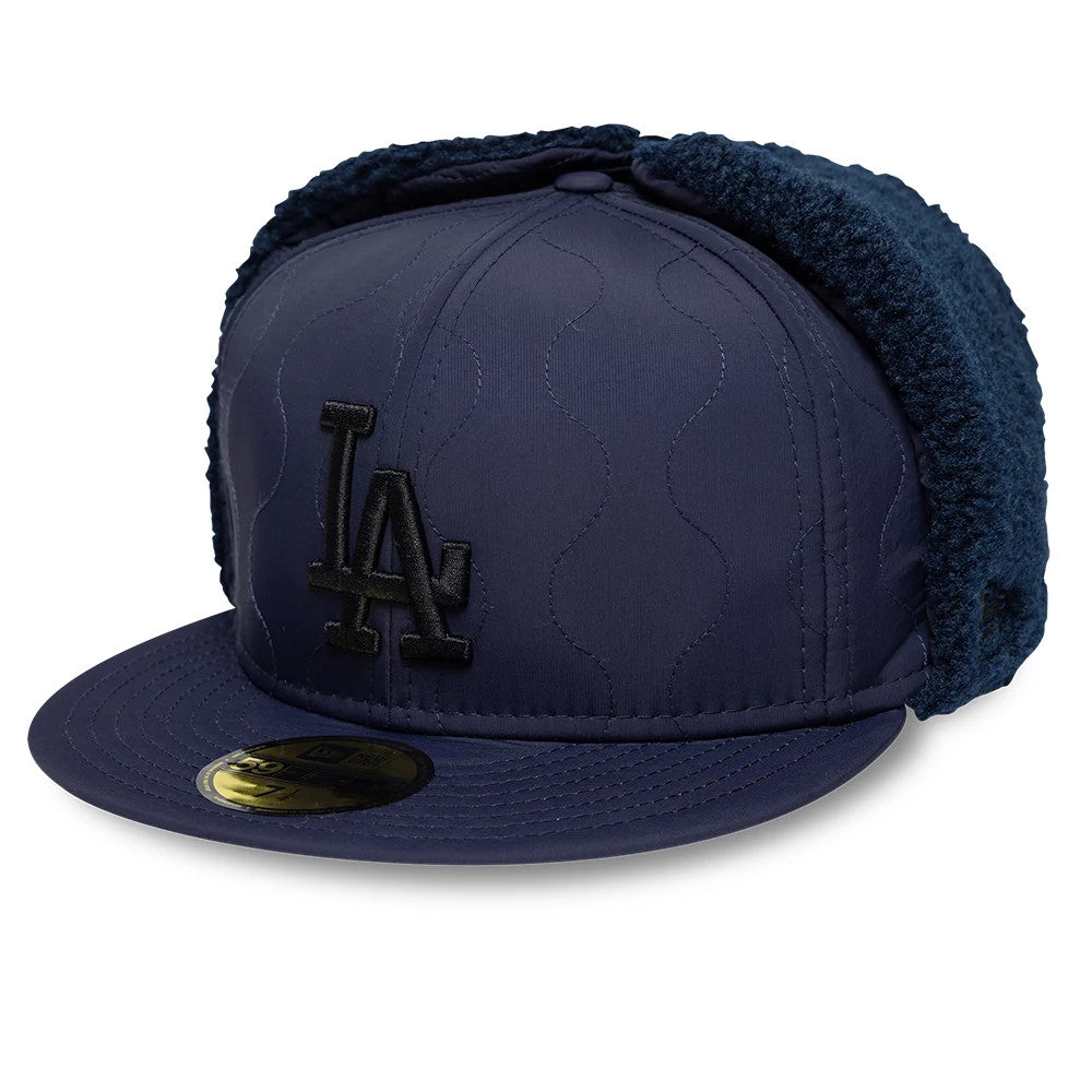 LA Dodgers MLB Quilted Navy New Era Dogear 59FIFTY Fitted Cap, front view showing the black embroidered LA logo on the quilted navy front panel, a gold 59FIFTY size sticker on the flat visor, and quilted ear flaps with a soft texture.