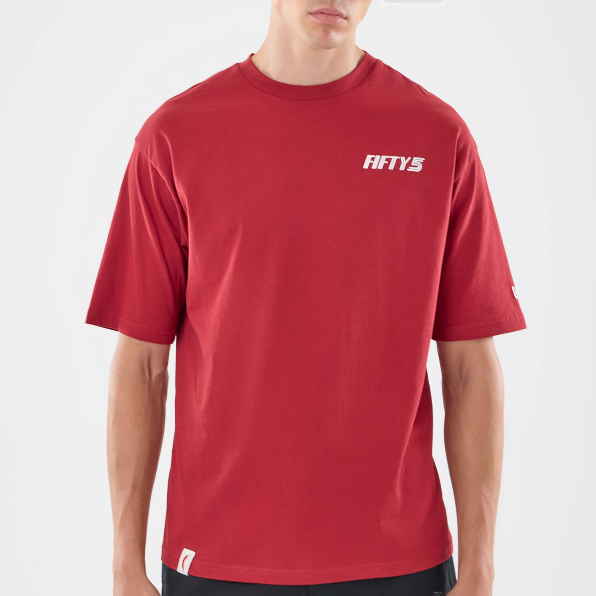 New Era Carlos Sainz Team Fifty5 Madrid Dark Red Oversized T-Shirt, front view showing the dark red fabric with a white printed FIFTY5 logo on the left chest, a New Era logo on the left sleeve, and a slightly relaxed fit styled on a model.