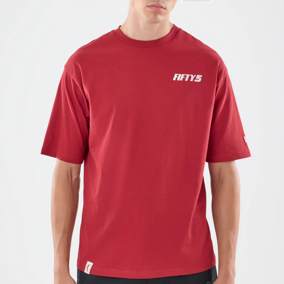 New Era Carlos Sainz Team Fifty5 Madrid Dark Red Oversized T-Shirt, front view showing the dark red fabric with a white printed FIFTY5 logo on the left chest, a New Era logo on the left sleeve, and a slightly relaxed fit styled on a model.