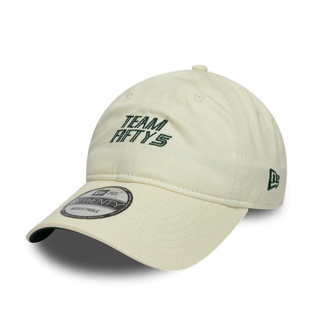 Carlos Sainz Team Fifty5 Cream New Era 9TWENTY Adjustable Cap, three-quarter view showing raised green embroidered Team Fifty5 text on the front panel, curved cream visor with a 9TWENTY size sticker, and green New Era flag logo on the left side.