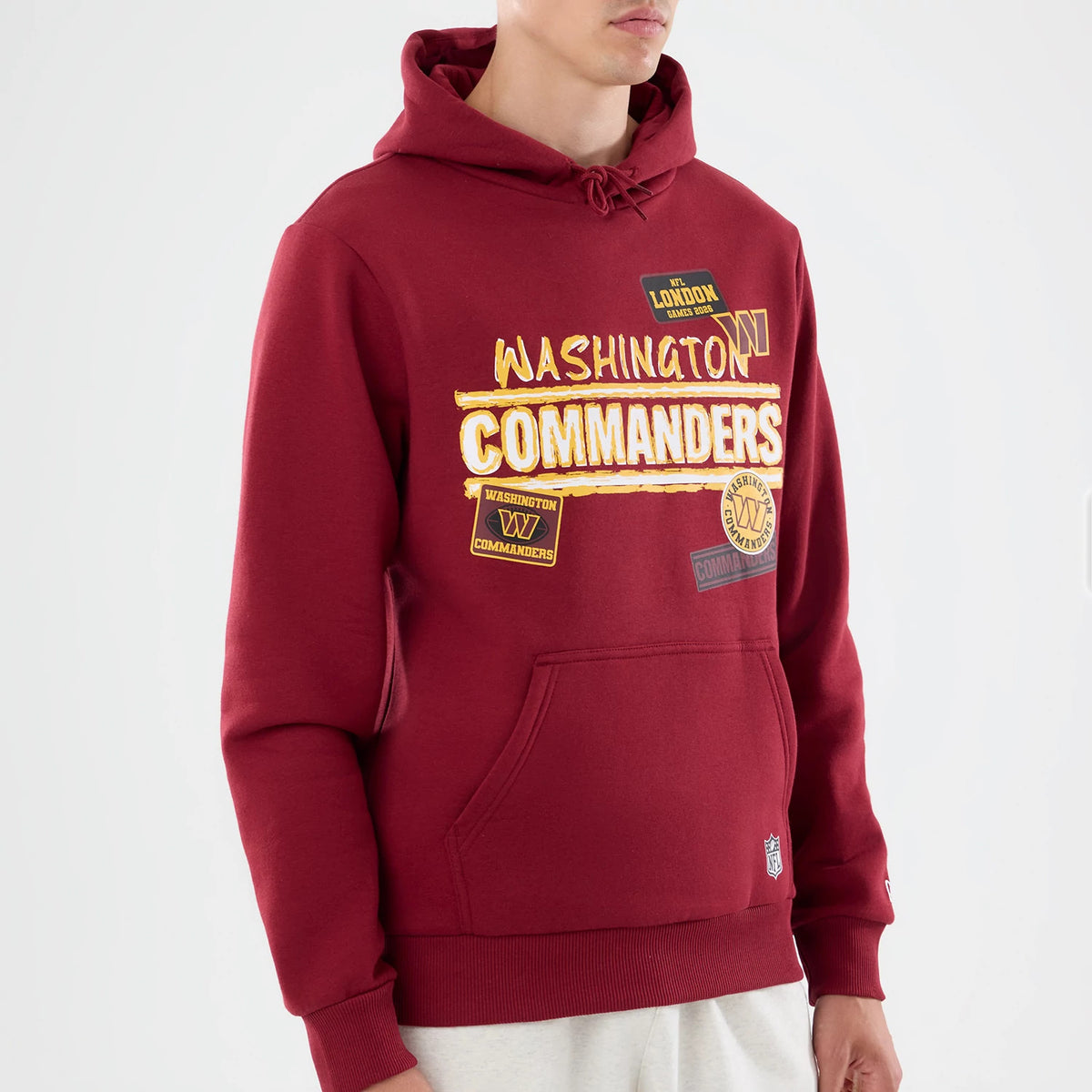 New Era Washington Commanders NFL Patch Dark Red Pullover Hoodie, front view on a model displaying multiple patches including Washington Commanders in lettering across the chest, a kangaroo pocket.