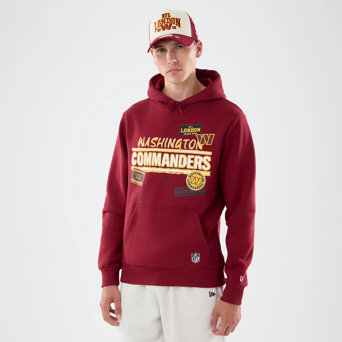 New Era Washington Commanders NFL Patch Dark Red Pullover Hoodie, front view on-model displaying prominent Washington Commanders gold and white embroidered lettering across the chest, additional patch details below.