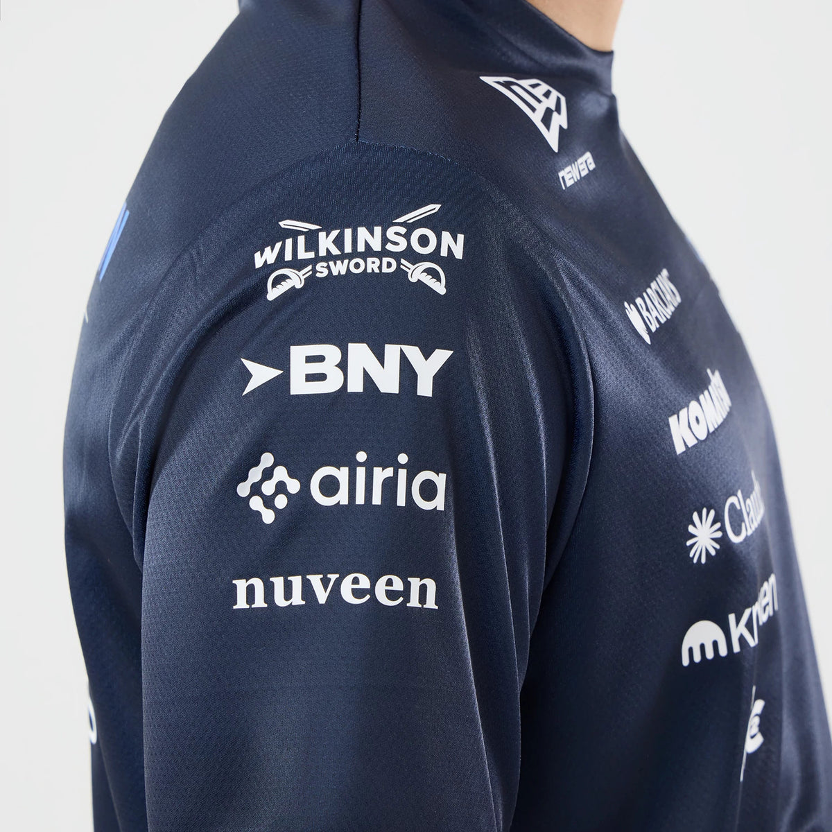 New Era Williams Singapore Navy Tech T-Shirt, side view showing various white sponsor logos on the navy sleeves, including Wilkinson Sword, BNY, and airia, with a raised New Era logo on the shoulder.