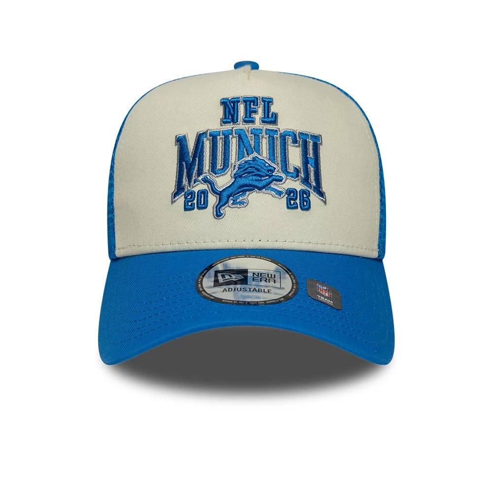 Lions NFL International Games 2026 Munich Blue New Era 9FORTY A-Frame Trucker Adjustable Cap, front view showing the raised blue embroidered NFL Munich 2026 logo with a lion on the cream front panels.