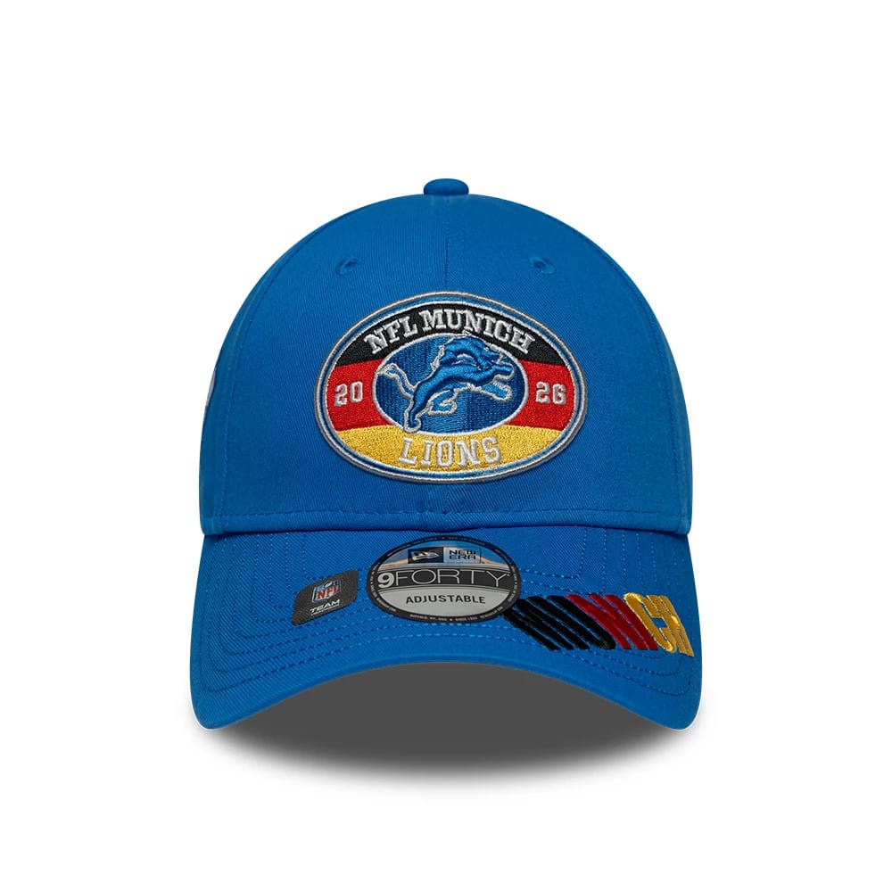 Detroit Lions NFL International Games 2026 Munich Blue New Era 9FORTY Adjustable Cap, front view showing a multicoloured emblem featuring the Detroit Lions logo and NFL Munich 2026 text, with a curved blue visor and 9FORTY size sticker on top.