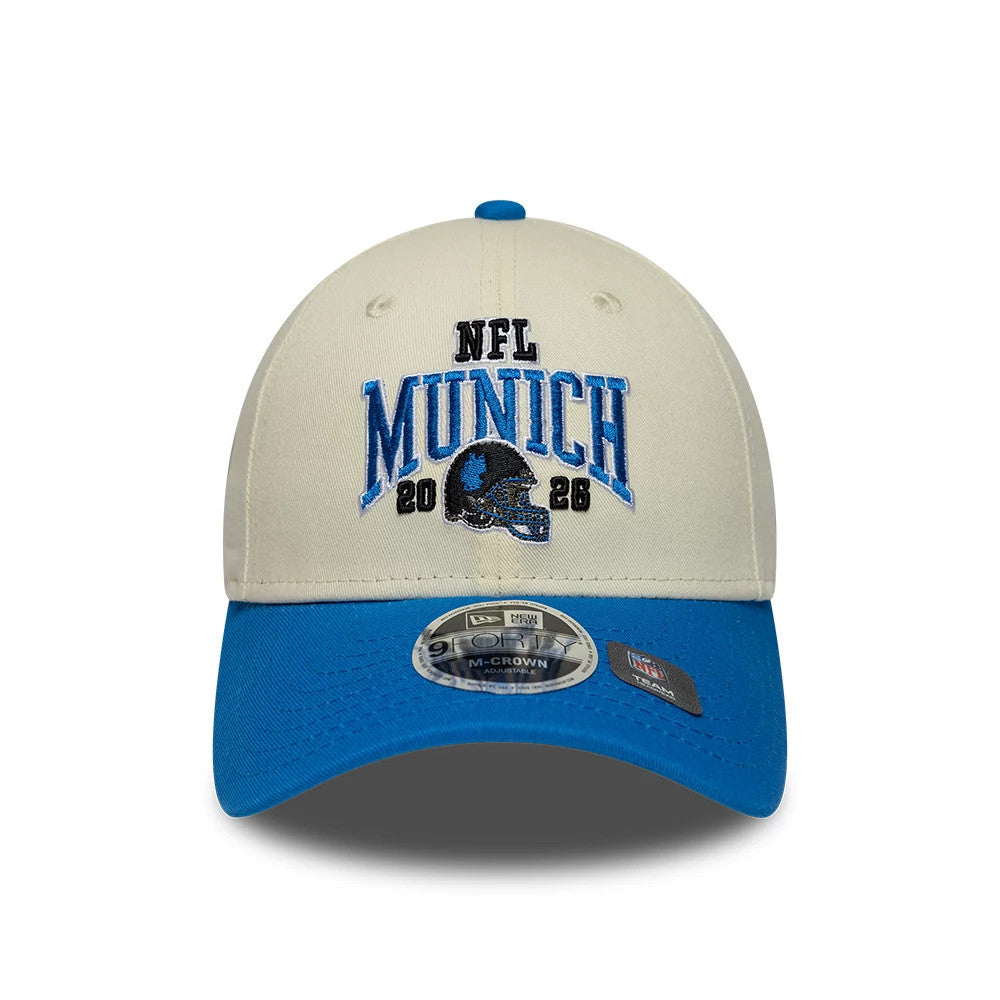 Lions NFL International Games 2026 Munich White & Blue New Era 9FORTY M-Crown Adjustable Cap, front view showing the blue NFL Munich lettering and black Lions helmet embroidered on the cream crown.