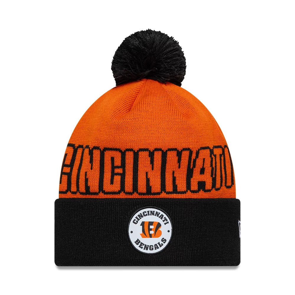 New Era Cincinnati Bengals NFL International Games 2026 Madrid Orange Cuff Knit Beanie Hat, front view showing the black BENGALS lettering on the orange knit crown, with a black pom-pom on top and a black cuff featuring the team logo patch.