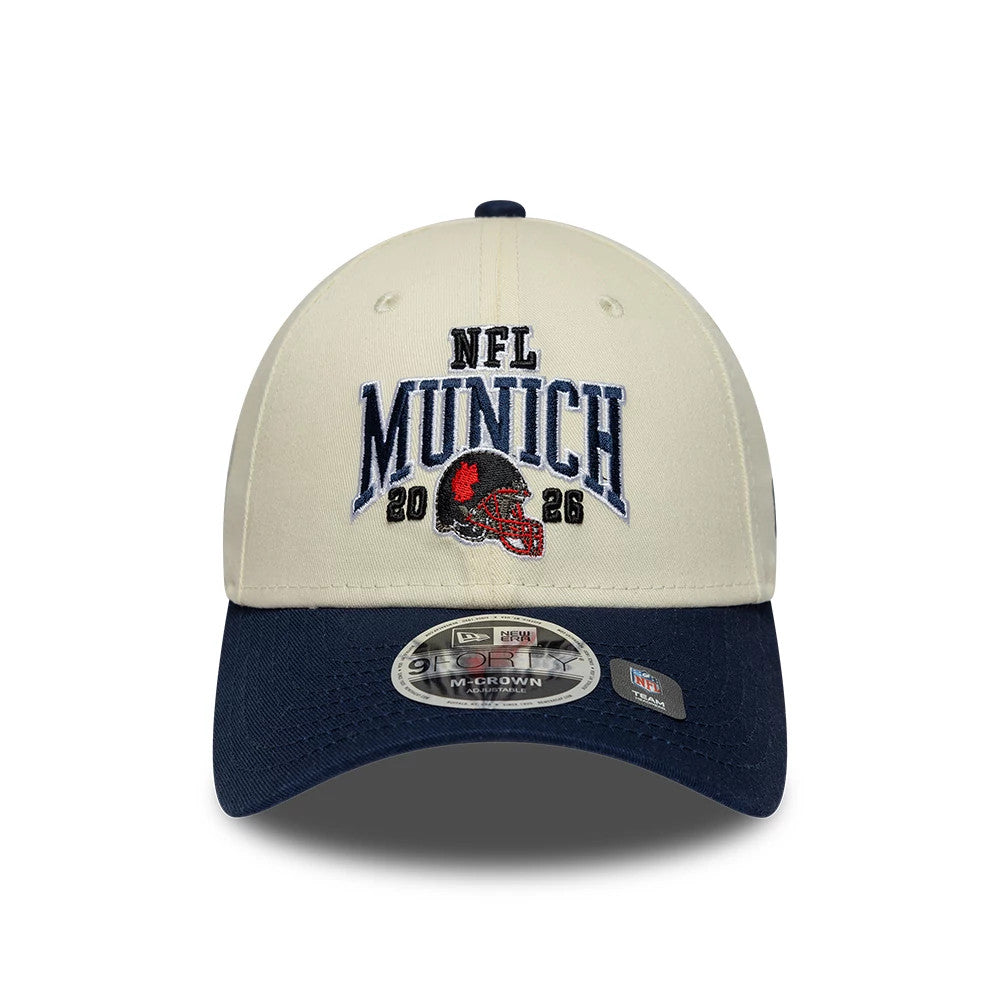 Patriots NFL International Games 2026 Munich White & Dark Blue New Era 9FORTY M-Crown Adjustable Cap, front view showing the raised navy embroidered NFL Munich logo and a red and black helmet on the white crown, with a dark blue curved visor.