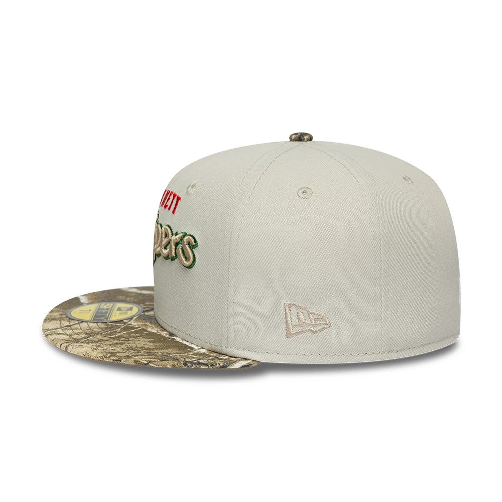 Gwinnett Stripers MiLB Hometown Sidepatch Beige New Era 59FIFTY Fitted Cap, side view showing the beige embroidered New Era flag logo on the left side, a camouflage-patterned flat visor with a gold 59FIFTY size sticker.