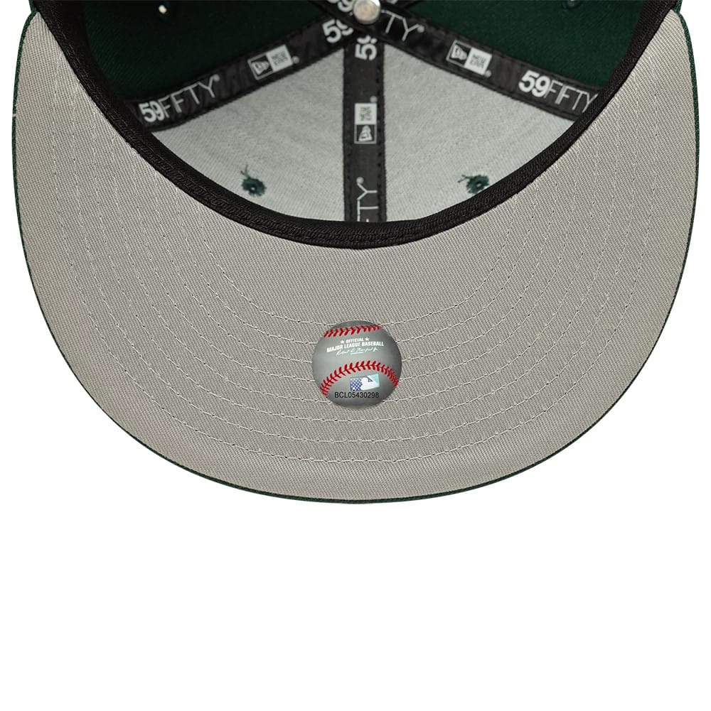 Athletics MLB Dark Green New Era 59FIFTY Fitted Cap, inside view showing grey undervisor with central baseball-themed sticker, black branded taping along the seams, and forest green crown interior, highlighted by eyelets.