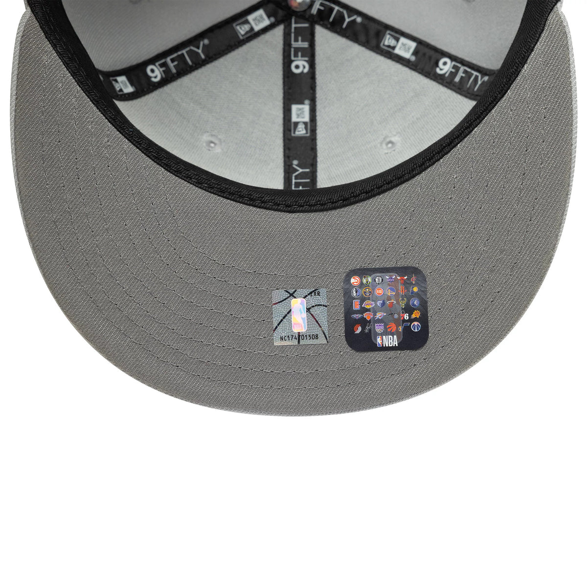 LA Lakers NBA Essential Pack Grey New Era 9FIFTY Snapback Adjustable Cap, inside view showing the grey undervisor with official NBA and multi-team logo stickers, black taping with repeated 9FIFTY text and New Era logos along the seams.