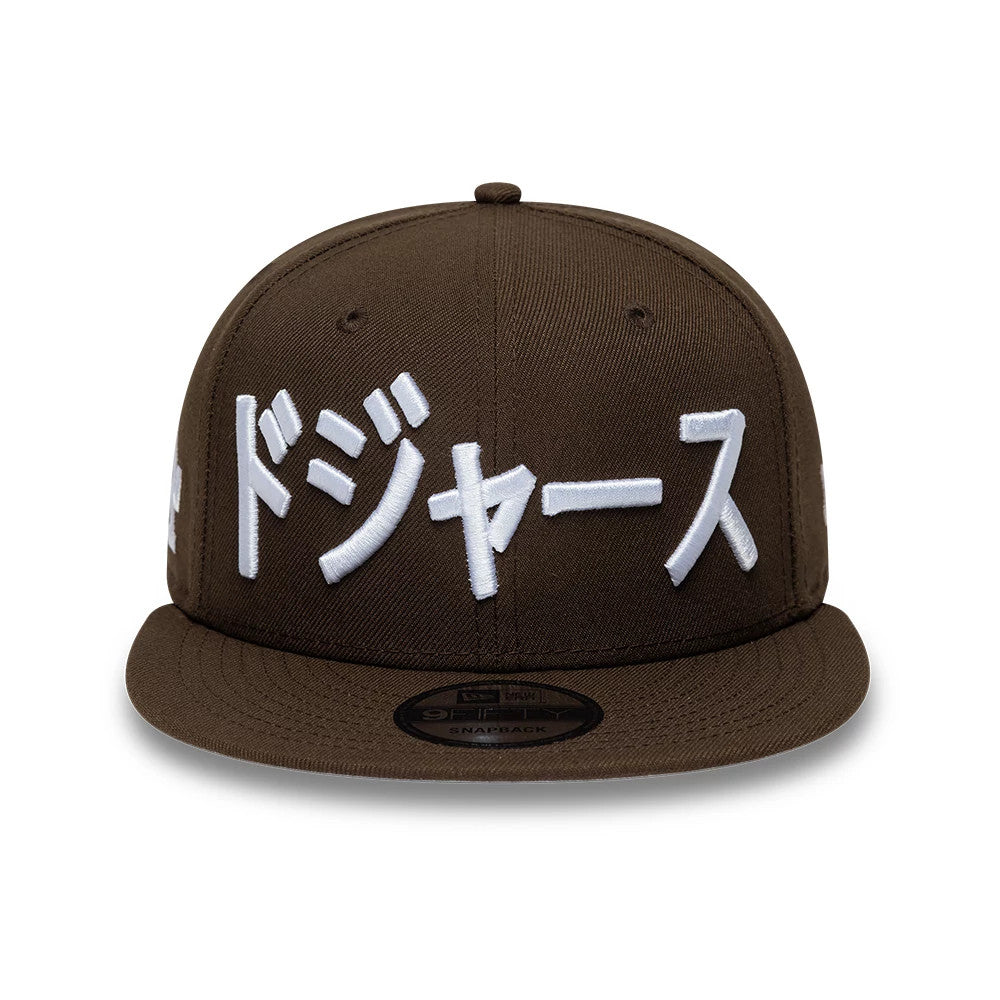LA Dodgers MLB Kanji Dark Brown New Era 9FIFTY Snapback Adjustable Cap, front view showing white raised embroidery of Kanji characters on the front panel, dark brown flat visor, and a black 9FIFTY size sticker on the top.