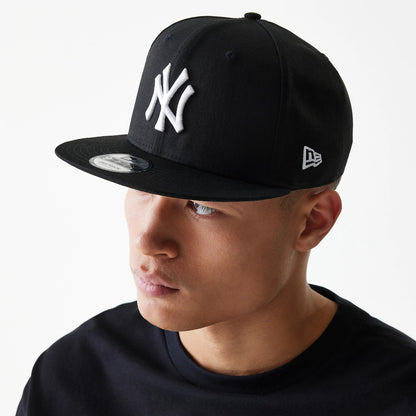 New York Yankees Black New Era 9FIFTY Cap, on-model three-quarter view with raised white NY logo on the front panel, silver New Era flag logo on the left side, and 9FIFTY size sticker on the black visor.
