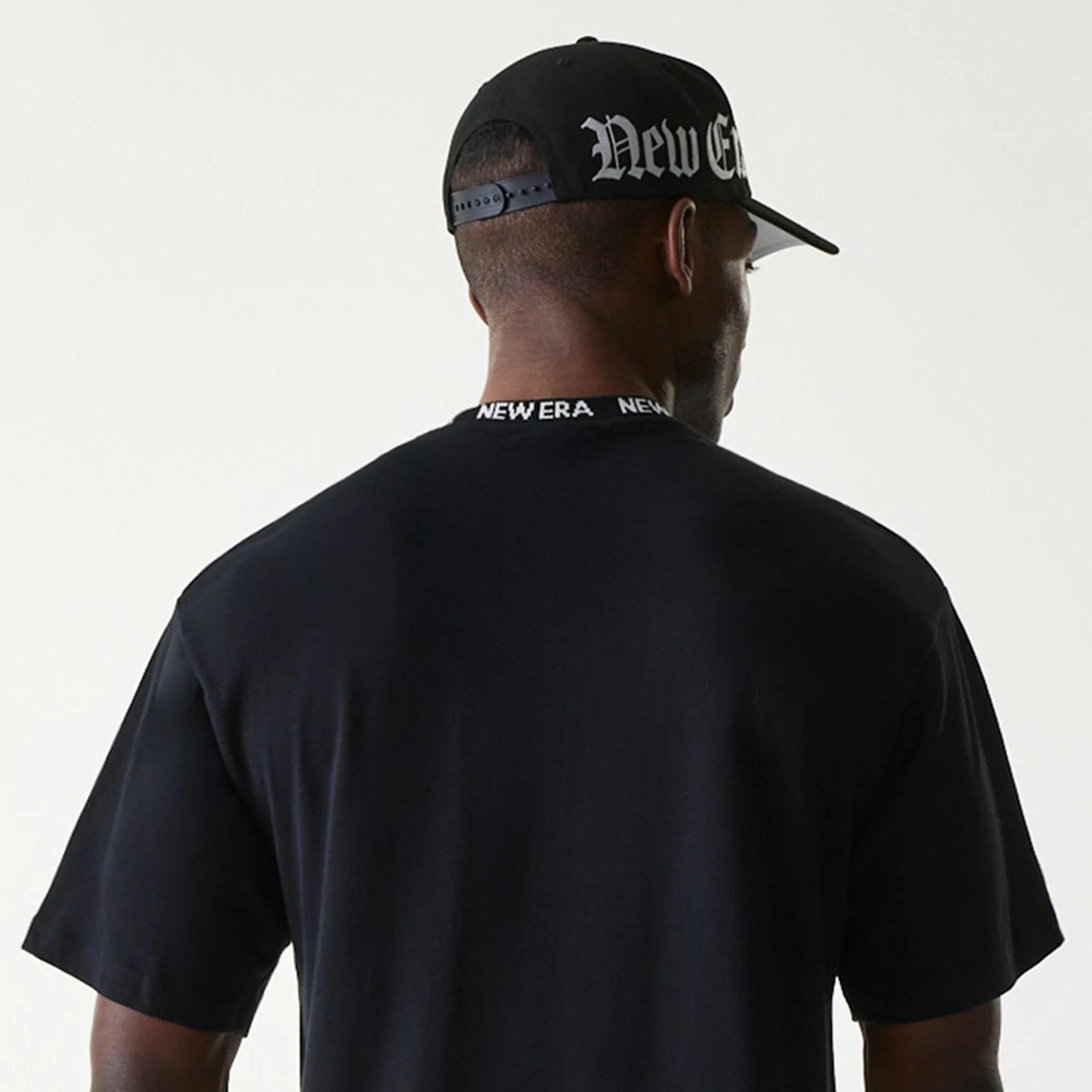 The Male model is wearing New Era Japan Neckband Logo Black T-Shirt 4