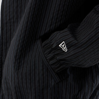 New Era Street Class Navy Jacket, close-up view showing the black and white pinstripe pattern on the sleeve, with a raised New Era logo embroidered near the cuff and a side pocket detail beneath.