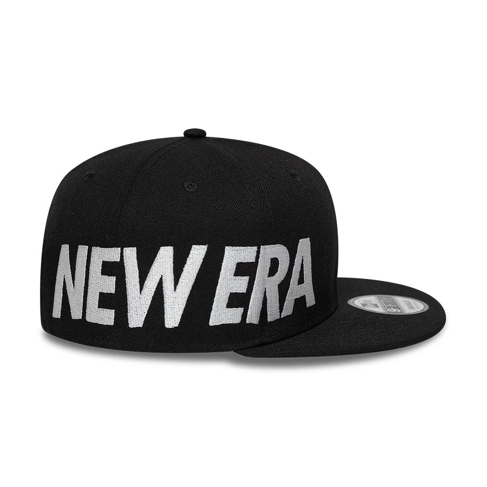 New Era Essential Black New Era 9FIFTY Snapback Adjustable Cap, three-quarter view showing bold white embroidered New Era logo across the front panel, a flat black visor with a silver 9FIFTY size sticker on top.