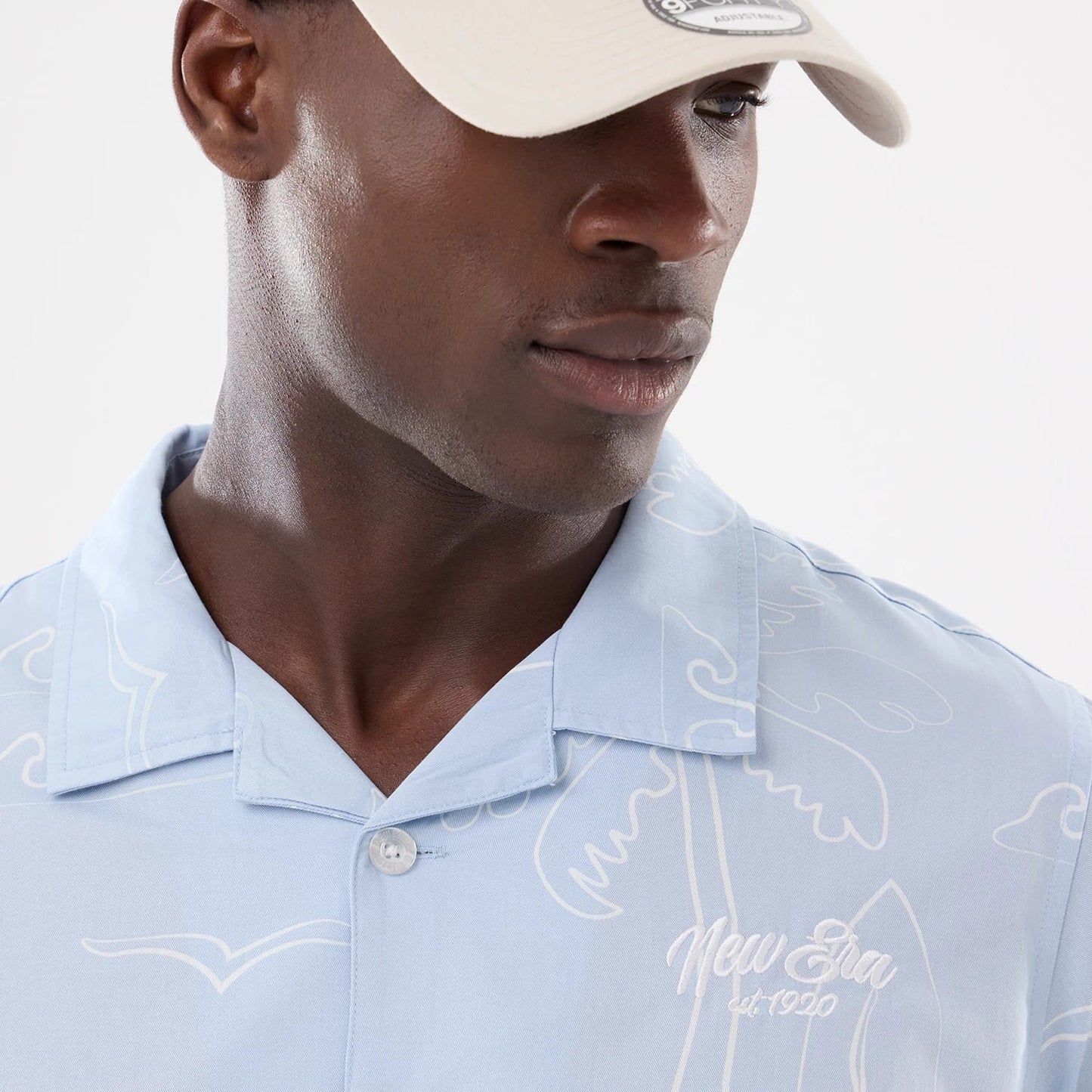 The model is wearing this New Era Resort Short Sleeve Shirt in blue. 5