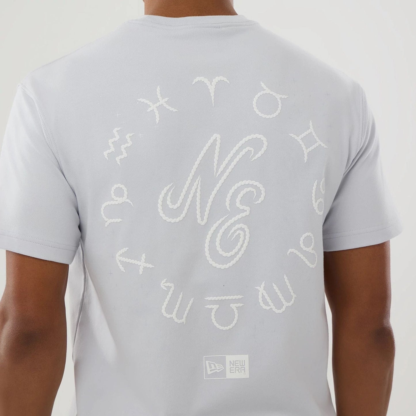 The model is wearing this New Era Zodiac Sign T-Shirt in silver. 3