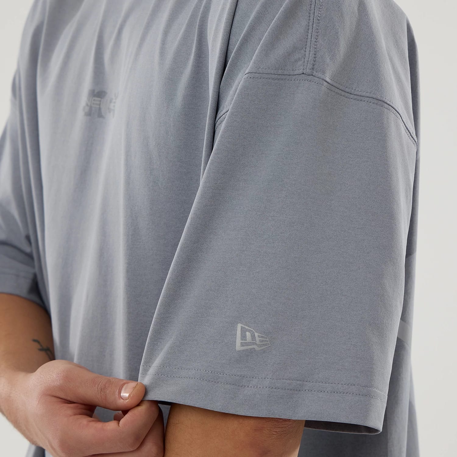 The model is wearing this New Era NEC Logo Oversized T-Shirt in grey. 5