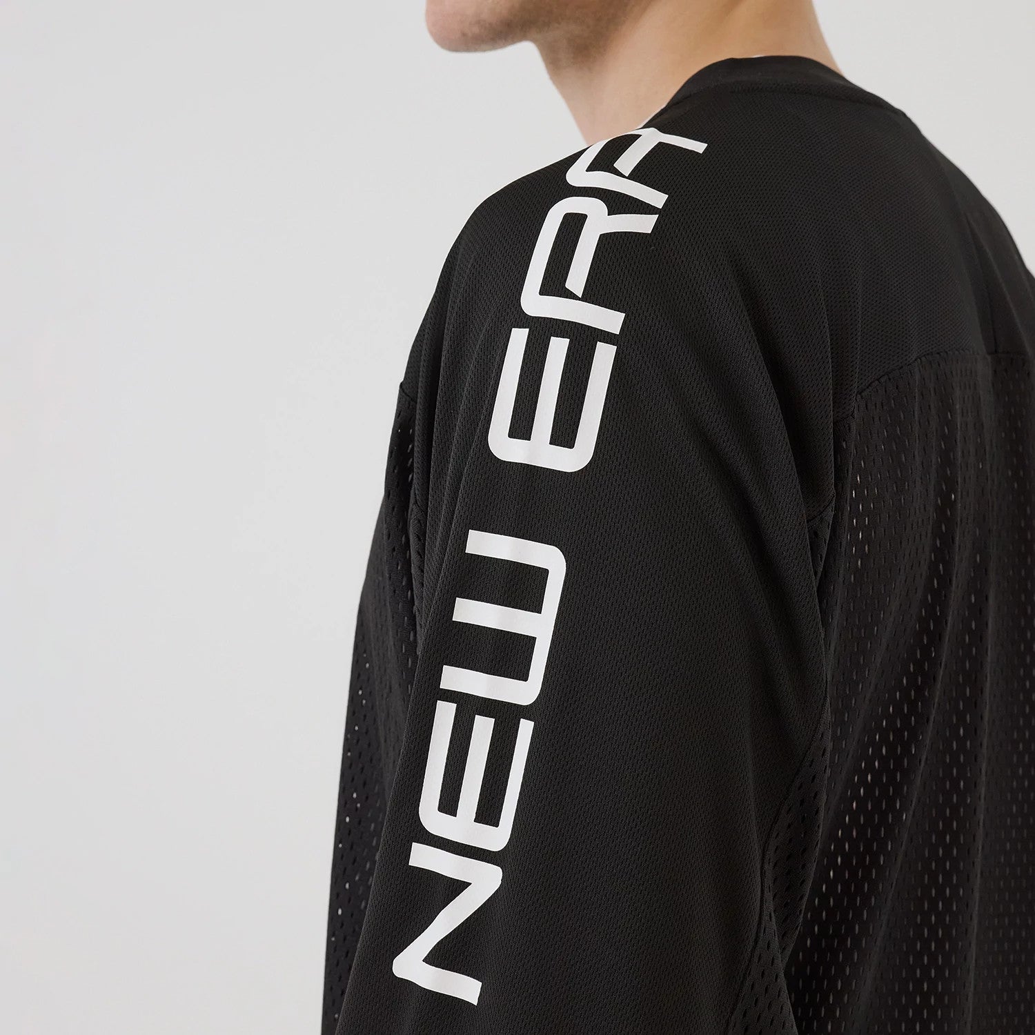 The model is wearing this New Era NEC Logo Long Sleeve Jersey in black. 4