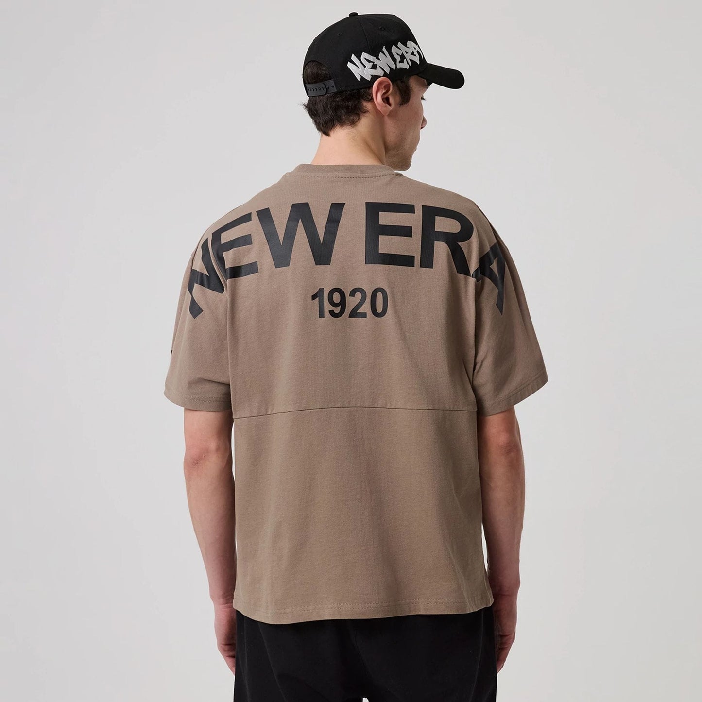 The model is wearing this New Era Distressed T-Shirt in Brown. 2