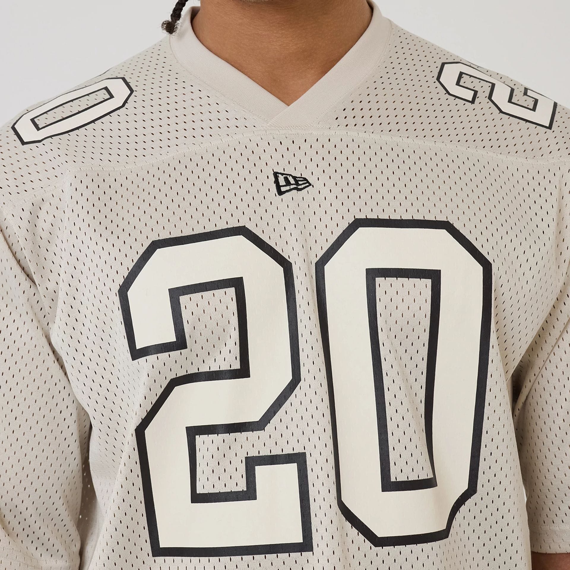 The model is wearing this New Era Mesh Football Short Sleeve Shirt in beige. 4