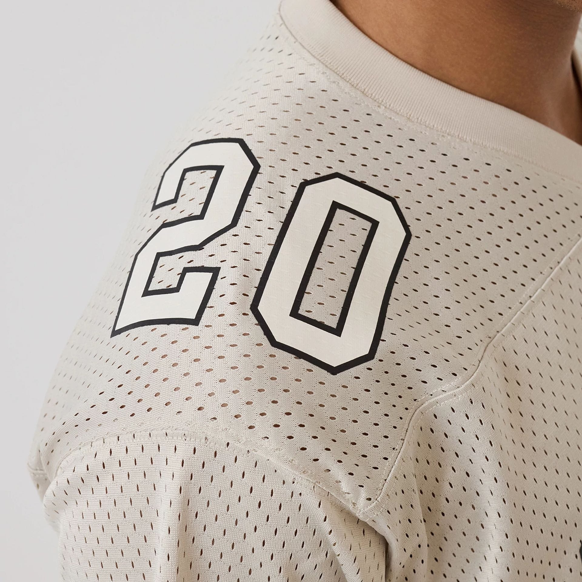 The model is wearing this New Era Mesh Football Short Sleeve Shirt in beige. 3