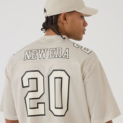 The model is wearing this New Era Mesh Football Short Sleeve Shirt in beige. 5