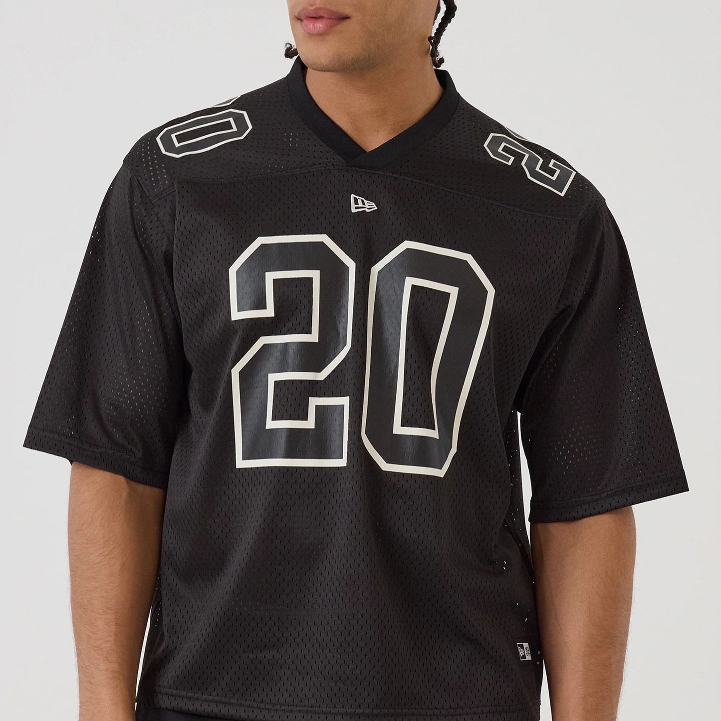 The model is wearing this New Era Mesh Football Short Sleeve Shirt in black. 5