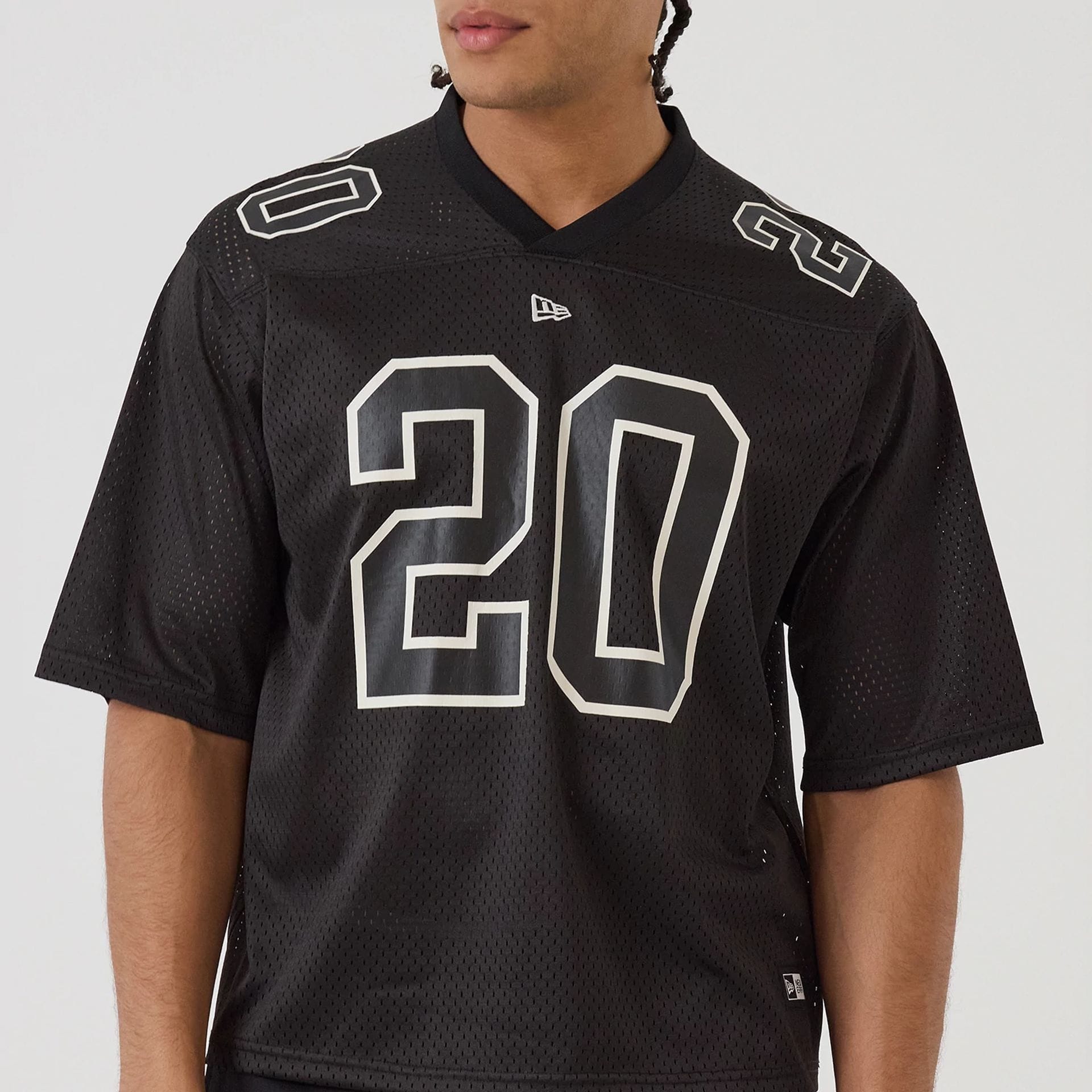 The model is wearing this New Era Mesh Football Short Sleeve Shirt in black. 5