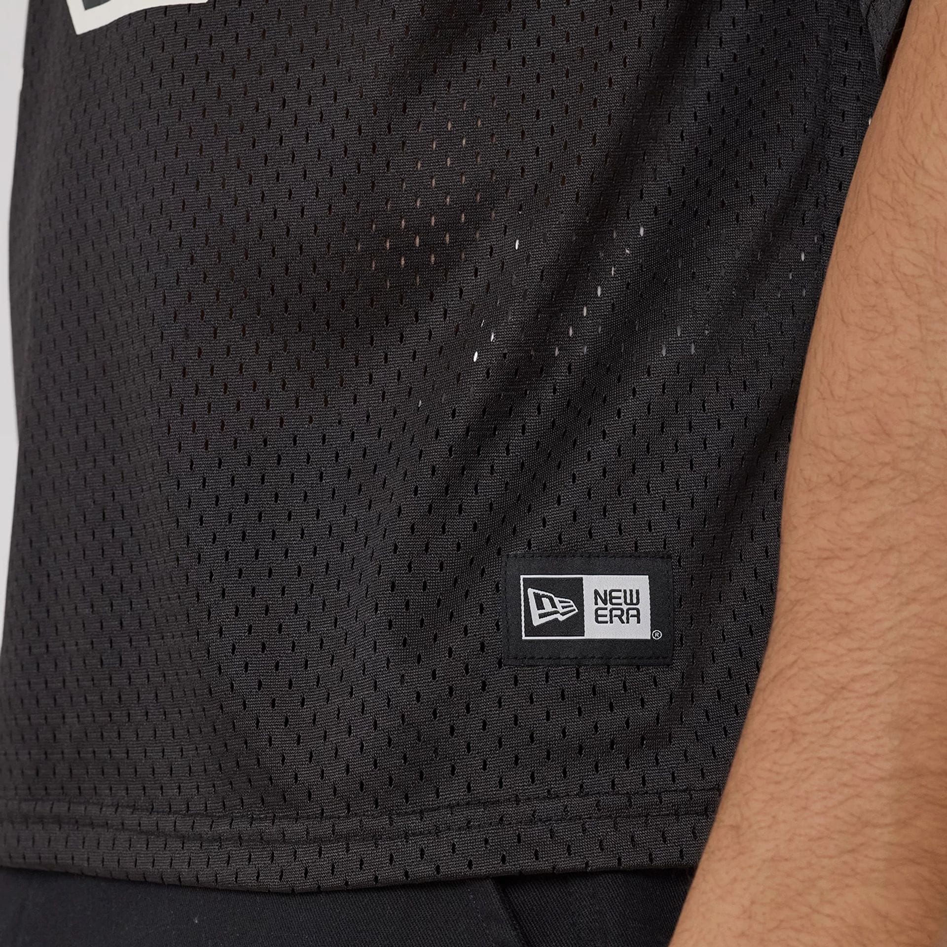 The model is wearing this New Era Mesh Football Short Sleeve Shirt in black. 6