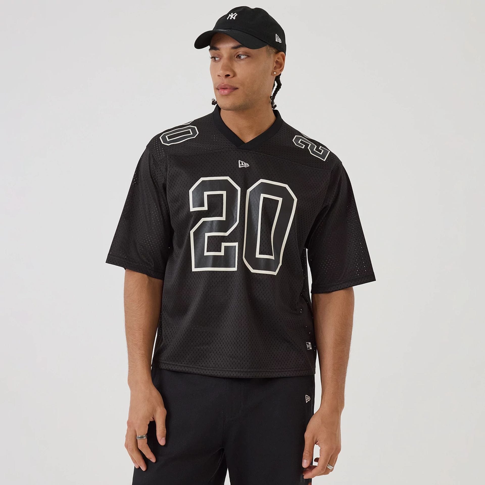 The model is wearing this New Era Mesh Football Short Sleeve Shirt in black. 1