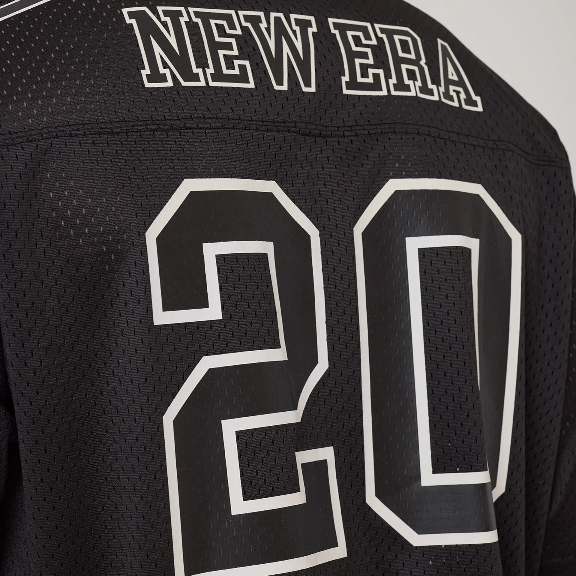 The model is wearing this New Era Mesh Football Short Sleeve Shirt in black. 7