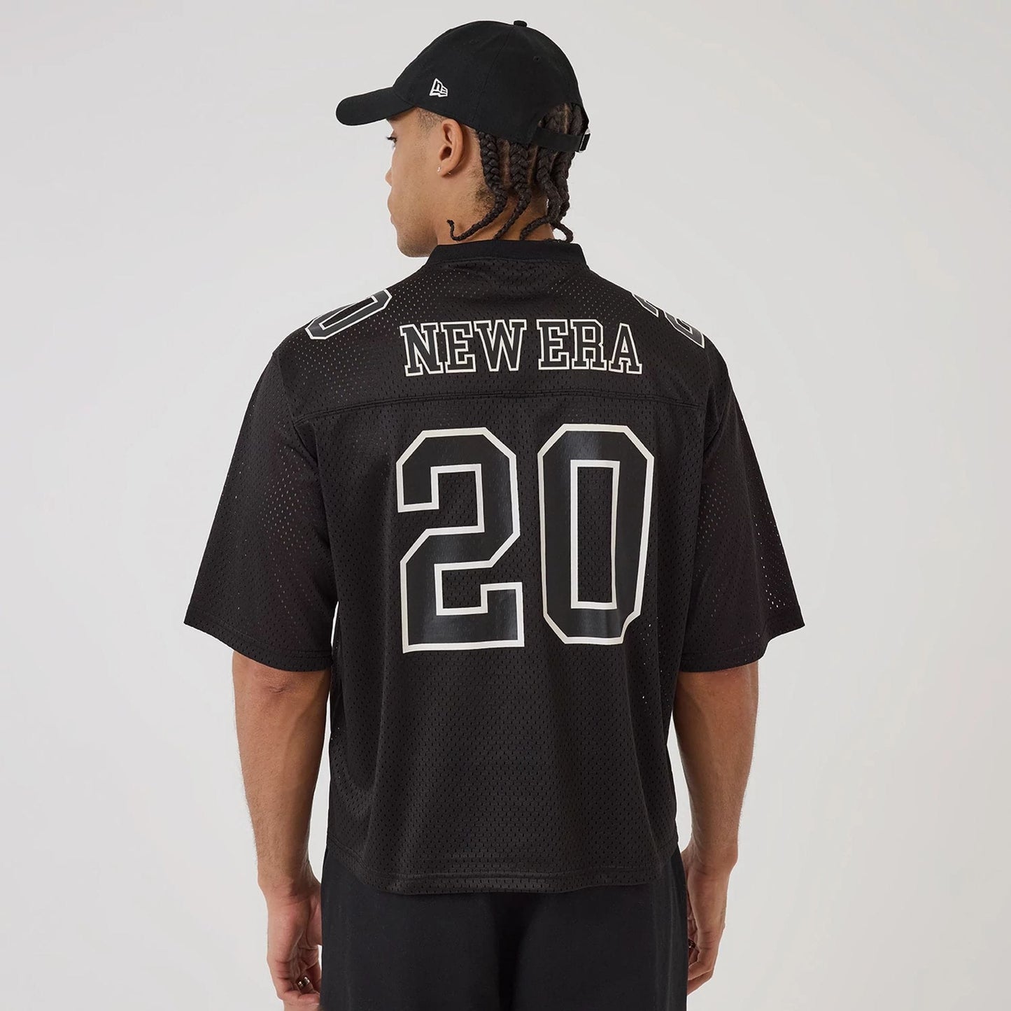 The model is wearing this New Era Mesh Football Short Sleeve Shirt in black. 2